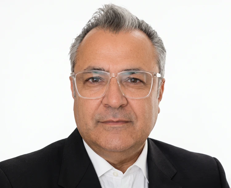 Professional portrait of a man wearing glasses and a black suit jacket over a white shirt on a white background.
